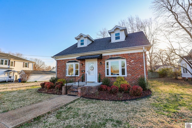 view of front facade featuring brick siding, a front lawn, and roof with shingles