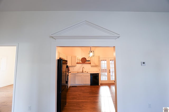 kitchen featuring black appliances, a sink, open shelves, light countertops, and dark wood-style flooring