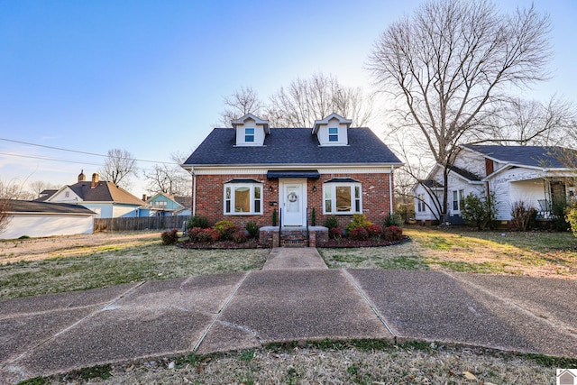 view of front of home with a front lawn, fence, brick siding, and roof with shingles