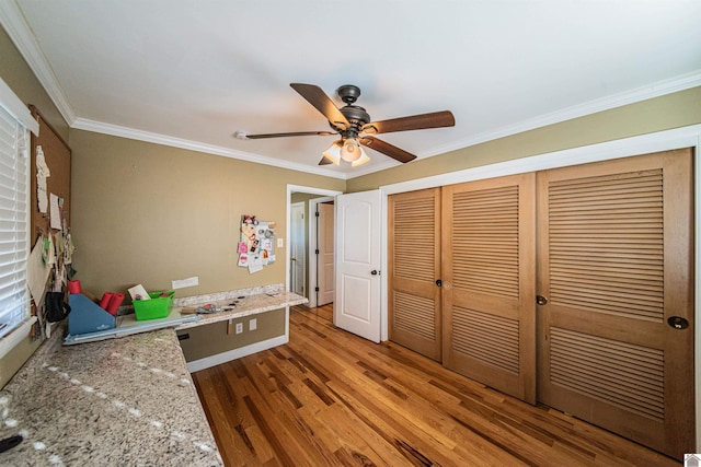 unfurnished bedroom featuring a ceiling fan, crown molding, wood finished floors, and a closet