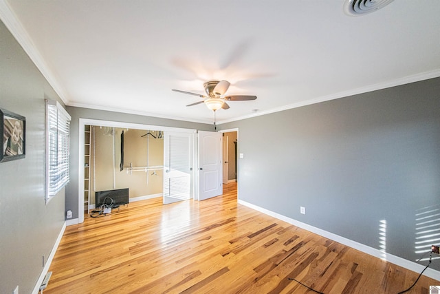 unfurnished bedroom featuring ornamental molding, a ceiling fan, wood finished floors, a closet, and baseboards