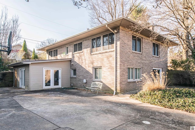 rear view of property featuring brick siding and fence