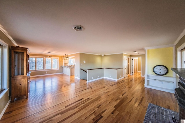 unfurnished living room with visible vents, baseboards, wood finished floors, and crown molding