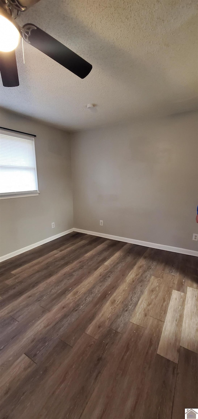 unfurnished room with dark wood finished floors, ceiling fan, a textured ceiling, and baseboards