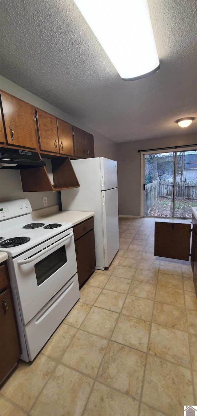 kitchen with under cabinet range hood, white appliances, a textured ceiling, and light countertops