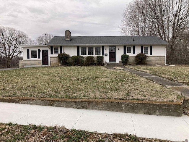 ranch-style home with stone siding, roof with shingles, a chimney, and a front yard