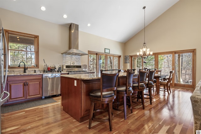 kitchen with dishwasher, light wood-style flooring, range, wall chimney exhaust hood, and a sink