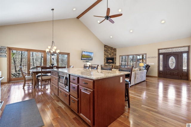 kitchen with beam ceiling, a breakfast bar, hardwood / wood-style flooring, decorative light fixtures, and stainless steel microwave