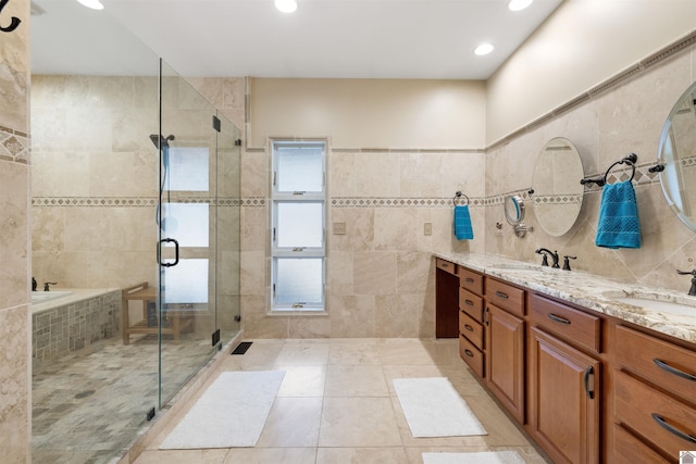 bathroom featuring double vanity, tile walls, a stall shower, and a sink