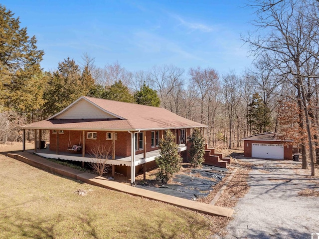 view of front of home with covered porch, an outdoor structure, a front lawn, a garage, and brick siding