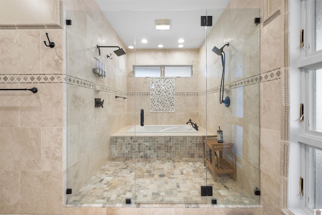 bathroom featuring tiled tub, a healthy amount of sunlight, and a shower stall