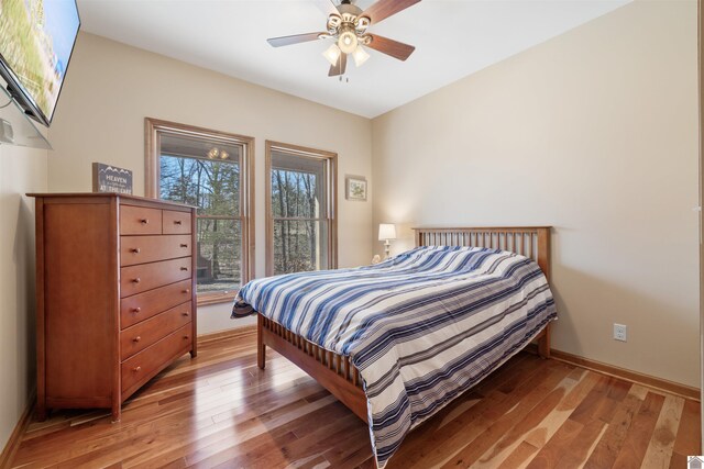 bedroom with light wood-style floors, baseboards, and ceiling fan