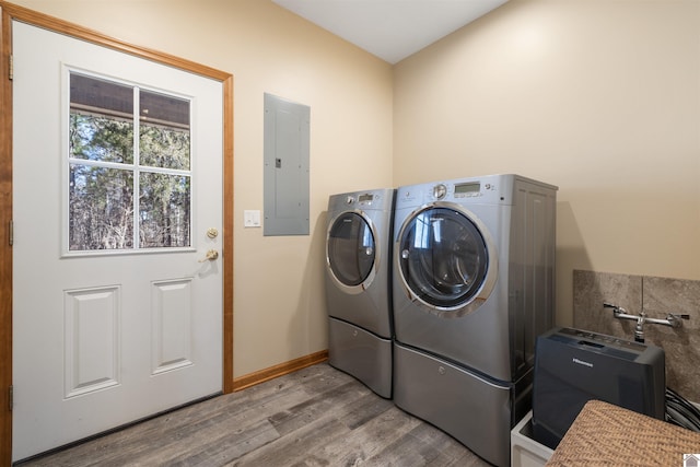 washroom with baseboards, washing machine and dryer, electric panel, laundry area, and wood finished floors