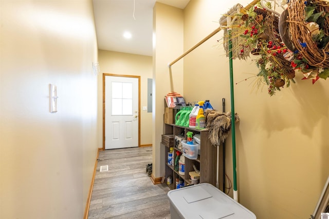 hall featuring electric panel, wood finished floors, and baseboards