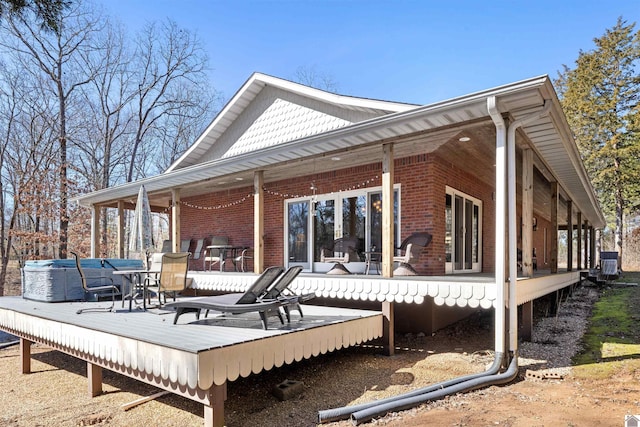 back of property featuring brick siding and a wooden deck