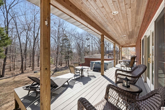 wooden deck featuring outdoor dining space and a hot tub