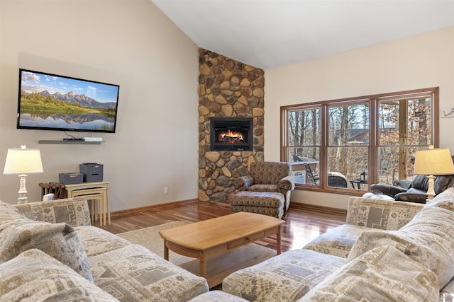 living area with baseboards, high vaulted ceiling, wood finished floors, and a fireplace