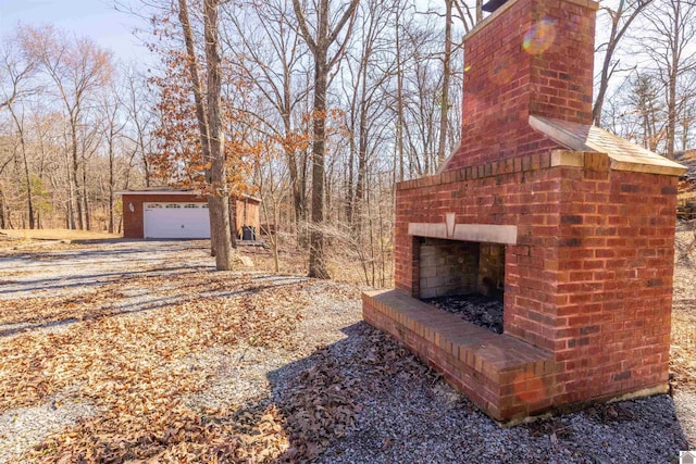 view of yard featuring an outdoor brick fireplace, driveway, and a garage