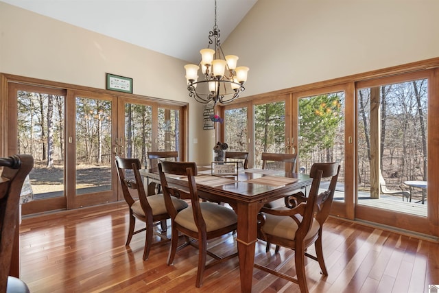 dining room with french doors, high vaulted ceiling, an inviting chandelier, and wood finished floors