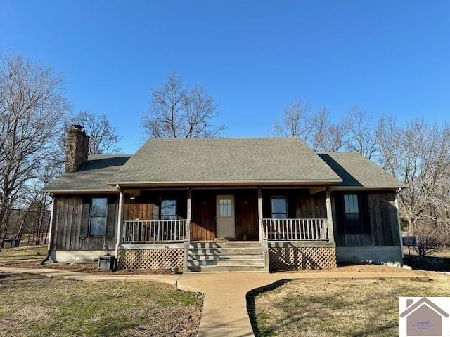 single story home featuring a shingled roof, covered porch, and a chimney