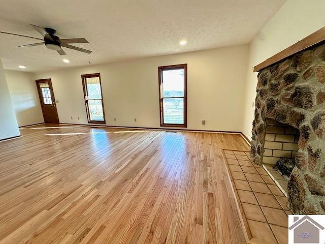 unfurnished living room with a ceiling fan, recessed lighting, light wood-style floors, and a textured ceiling