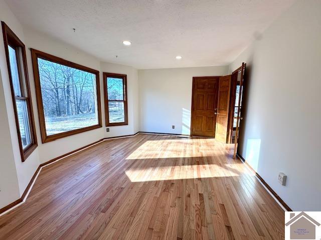 empty room featuring recessed lighting, wood finished floors, baseboards, and a textured ceiling