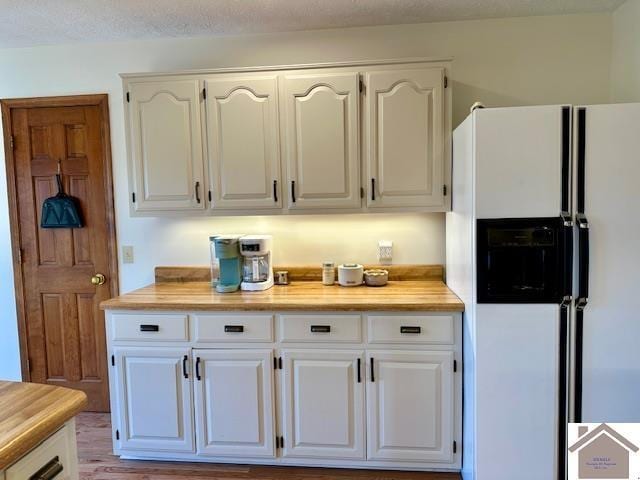 kitchen featuring white cabinets and white refrigerator with ice dispenser