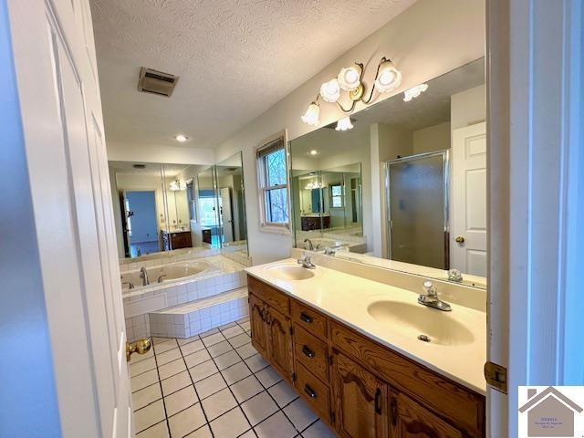 bathroom featuring tile patterned flooring, a shower stall, a textured ceiling, and a sink