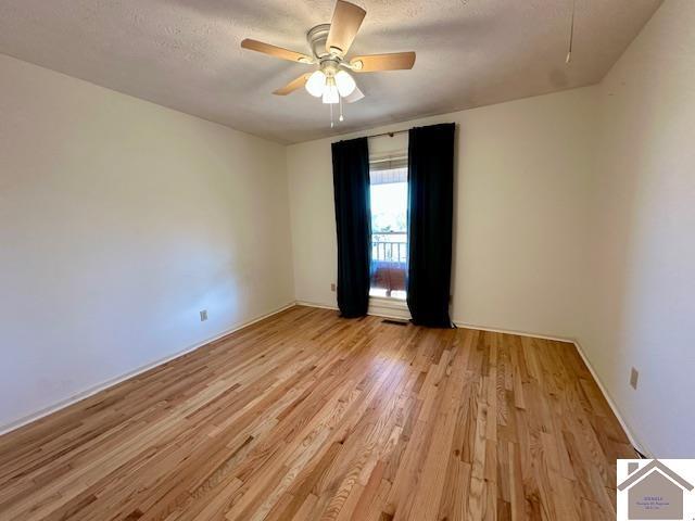 unfurnished room with visible vents, a ceiling fan, a textured ceiling, light wood finished floors, and attic access