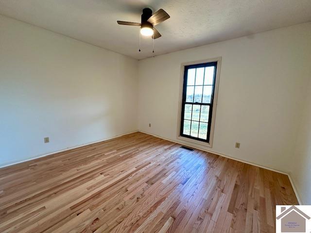 spare room featuring light wood-style floors, visible vents, and ceiling fan