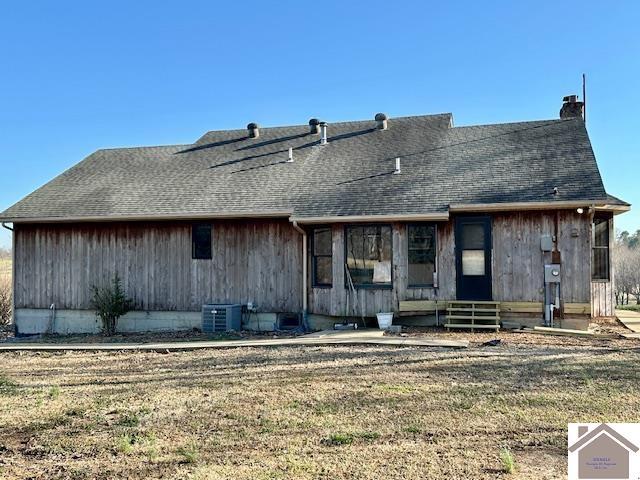 back of property featuring central air condition unit, a lawn, a shingled roof, and entry steps