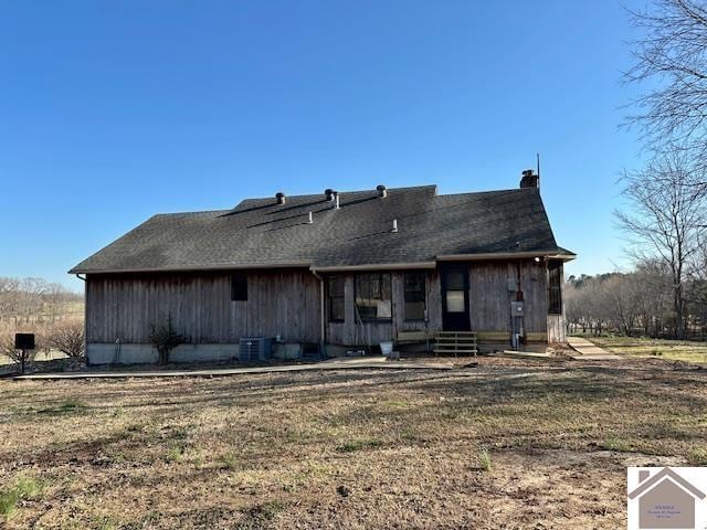 back of house with entry steps, cooling unit, and a lawn