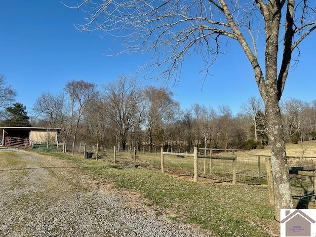 view of yard with a rural view, an outdoor structure, a pole building, and fence