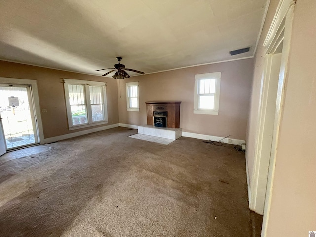 unfurnished living room featuring carpet, baseboards, visible vents, ceiling fan, and a tile fireplace