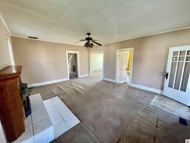 unfurnished living room with visible vents, ceiling fan, baseboards, carpet, and ornamental molding