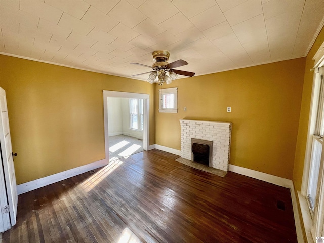 unfurnished living room with ceiling fan, a brick fireplace, baseboards, and wood finished floors