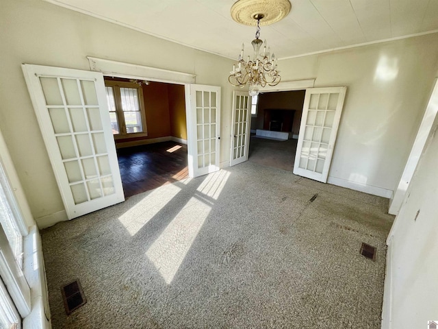 unfurnished dining area with baseboards, visible vents, french doors, crown molding, and a chandelier