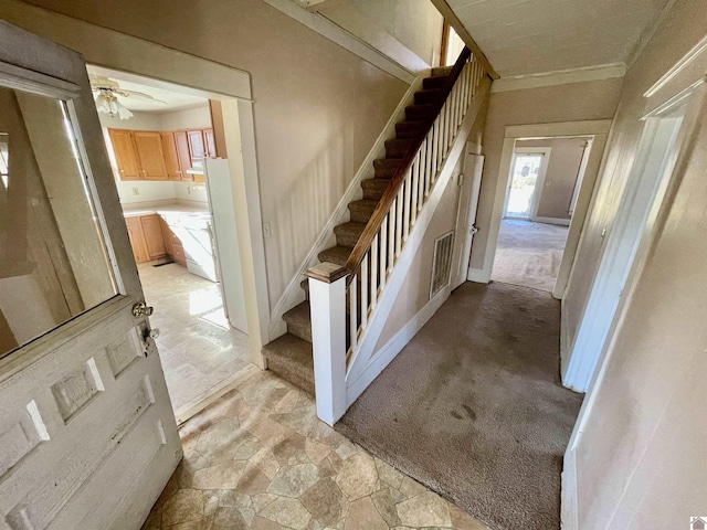 stairs featuring crown molding, carpet, visible vents, and stone finish flooring