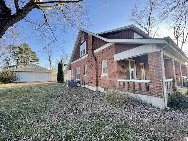 view of side of property with a detached garage, brick siding, central AC unit, and an outdoor structure