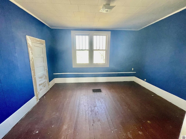 unfurnished room featuring visible vents, baseboards, hardwood / wood-style floors, and ornamental molding