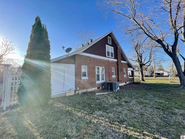 back of house with cooling unit, a lawn, and brick siding