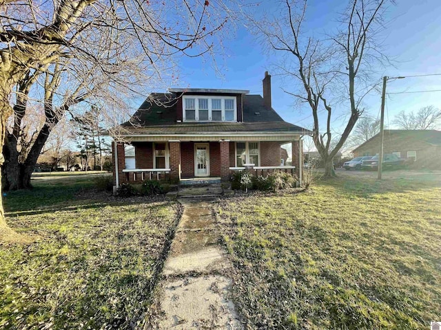 bungalow-style house featuring a front lawn, brick siding, covered porch, and a chimney