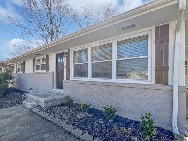 doorway to property with visible vents and brick siding