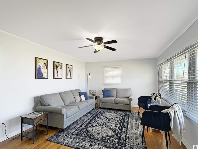 living room featuring ceiling fan, crown molding, baseboards, and wood finished floors