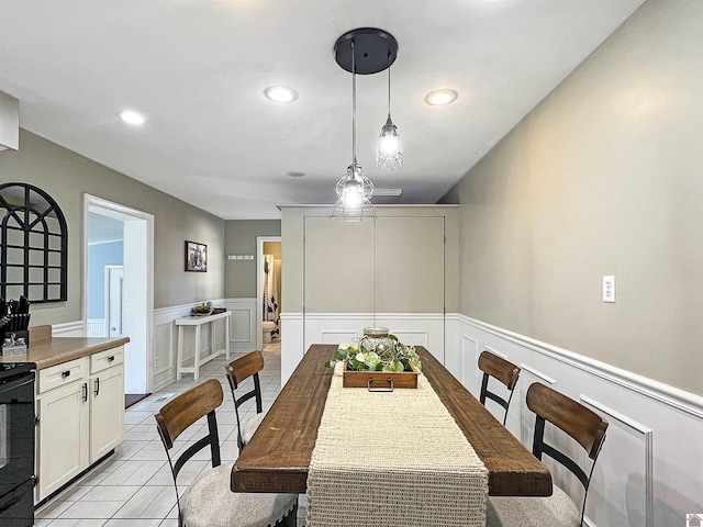 dining space featuring light tile patterned floors, recessed lighting, and wainscoting