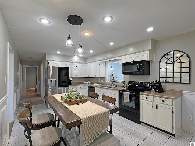 kitchen with black appliances, pendant lighting, recessed lighting, white cabinetry, and a sink