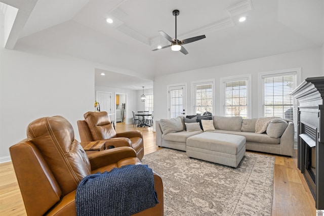 living area with recessed lighting, a fireplace, a tray ceiling, and light wood-style floors