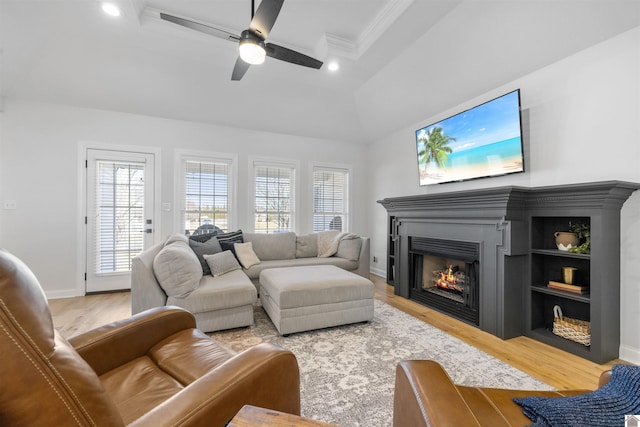 living room featuring a ceiling fan, baseboards, light wood finished floors, recessed lighting, and a warm lit fireplace