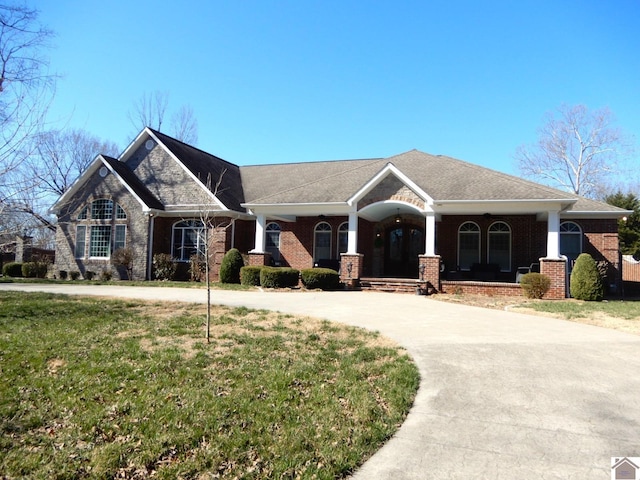 craftsman house with brick siding, concrete driveway, and a front lawn