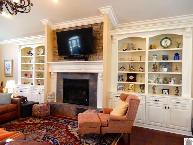 living area featuring a tiled fireplace, dark wood-style floors, crown molding, and built in features